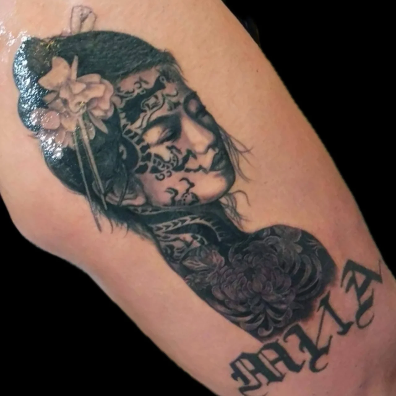 Black and grey realism portrait tattoo of a woman with ornamental face patterns, floral hairpin, chrysanthemum, and Maia script at Bloodline Tattoo Bangkok.