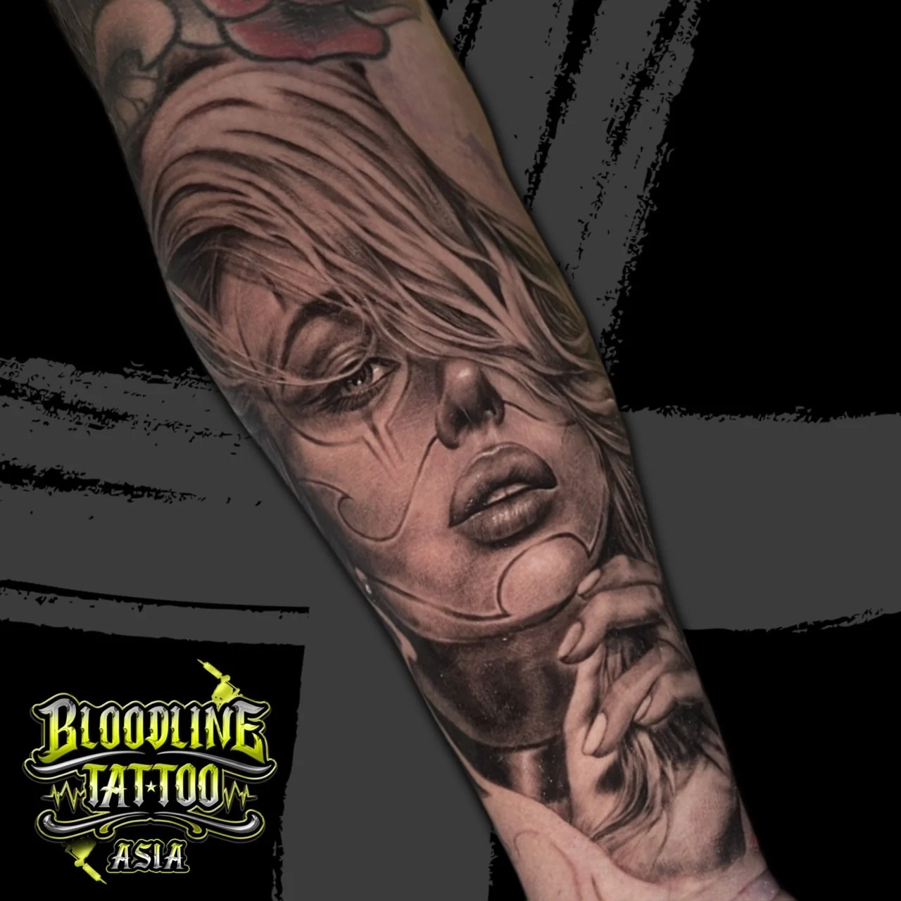 Black and grey Chicano forearm tattoo of a realistic payasa woman portrait with flowing hair and fine-line clown makeup at Bloodline Tattoo Bangkok.