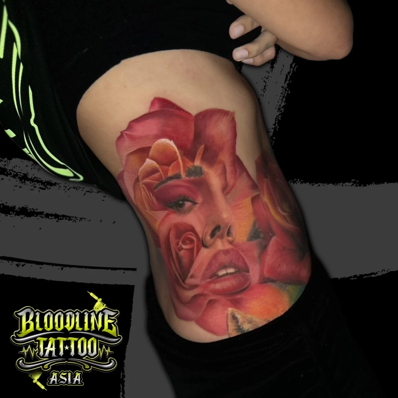 Colour surreal rib tattoo blending a woman's portrait with large red and pink roses on the side torso at Bloodline Tattoo Bangkok.