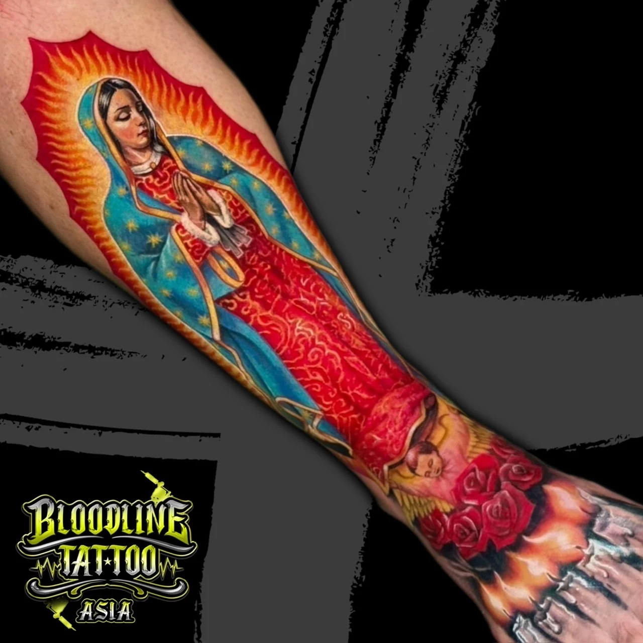 Colour Our Lady of Guadalupe forearm tattoo with blue star mantle, red roses, and lit candles on the hand at Bloodline Tattoo Bangkok.
