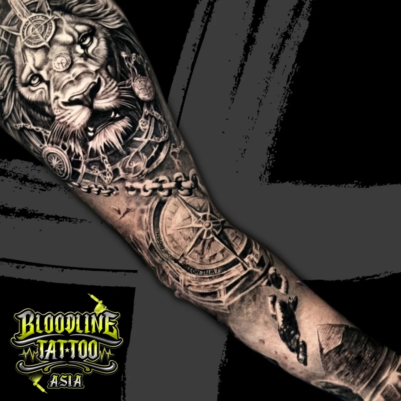 Arm tattoo with realistic lion portrait, compass rose forehead detail, metal chain, and large nautical compass in black and grey realism, at Bloodline Tattoo Bangkok.