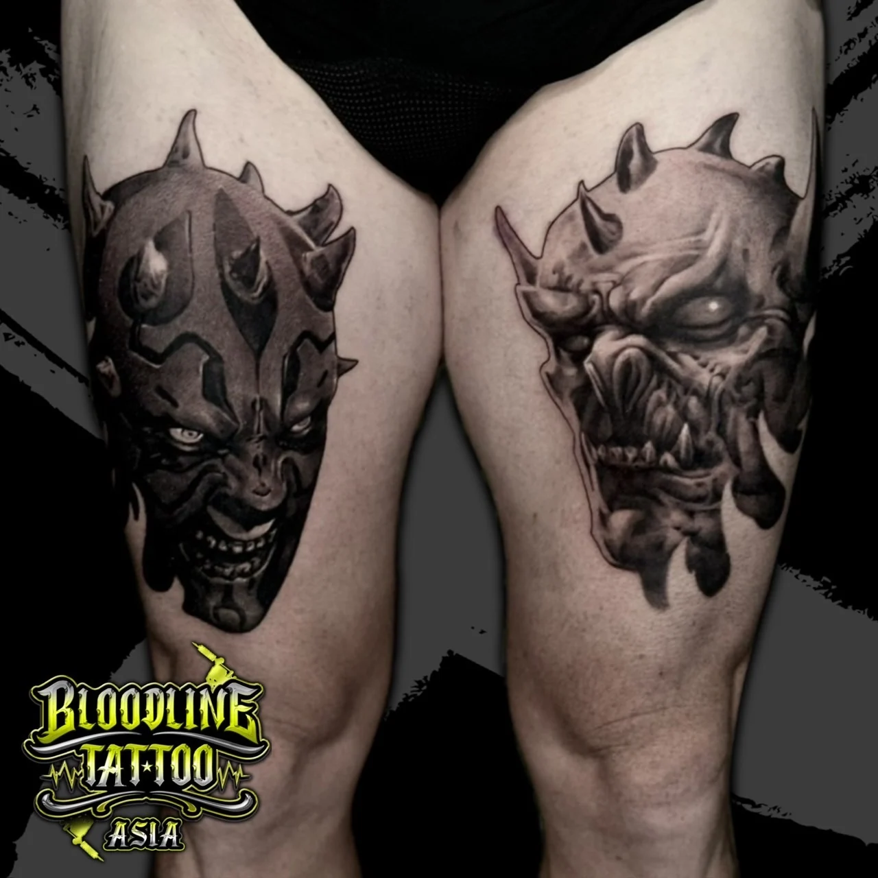 Black and grey portrait realism thigh tattoos of Darth Maul and a horned demonic creature with snarling teeth at Bloodline Tattoo Bangkok.