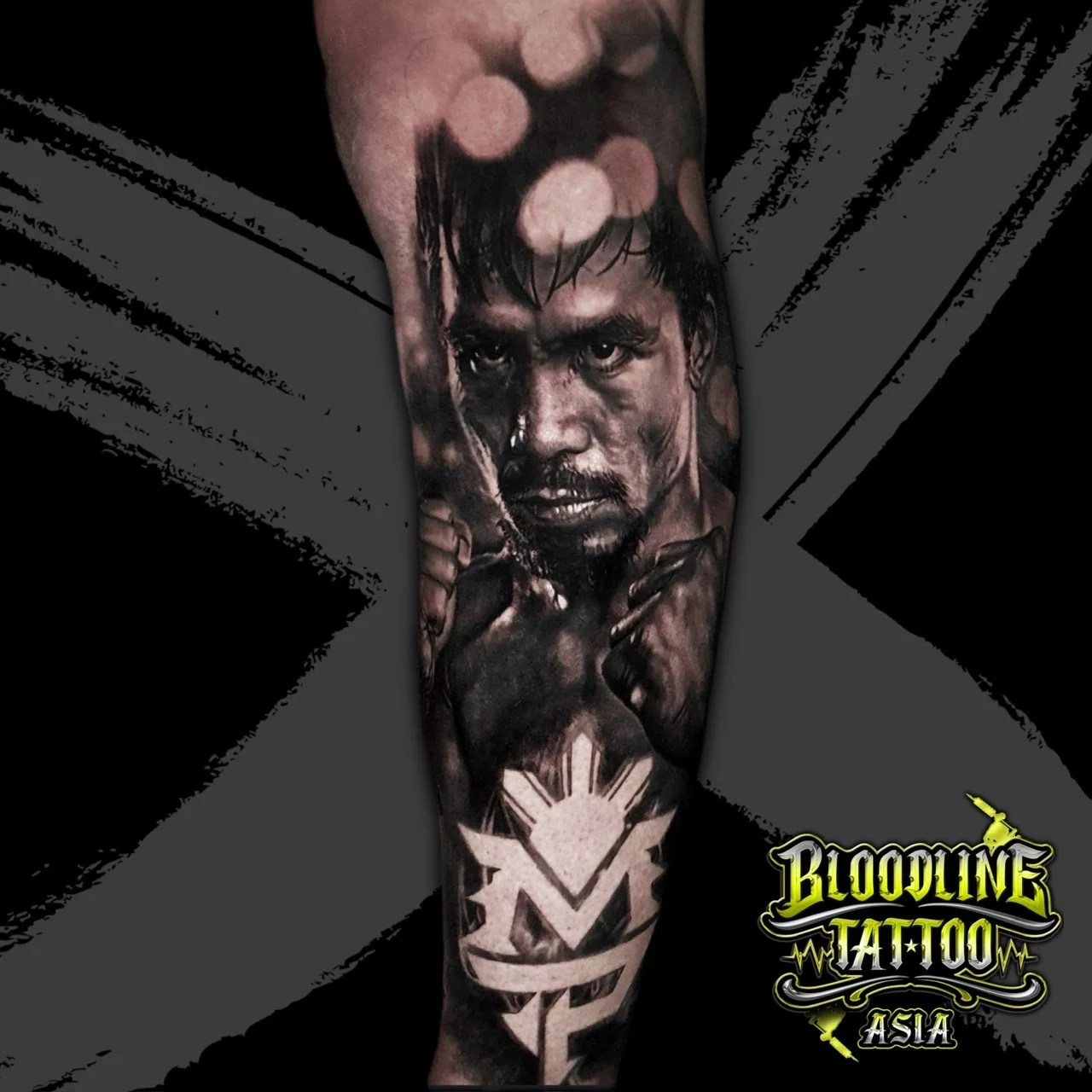 Black and grey portrait realism forearm tattoo of boxer Manny Pacquiao in fighting stance with his MP logo and Philippine sun at Bloodline Tattoo Bangkok.