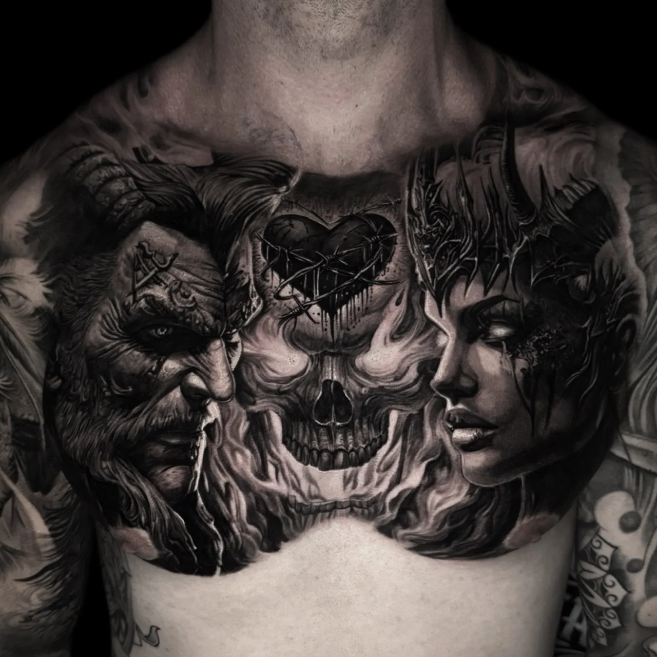 A black and grey realism chest tattoo with a barbed-wire heart above a skull, flanked by a horned bearded man and a thorn-crowned woman in smoky shading, at Bloodline Tattoo Bangkok.